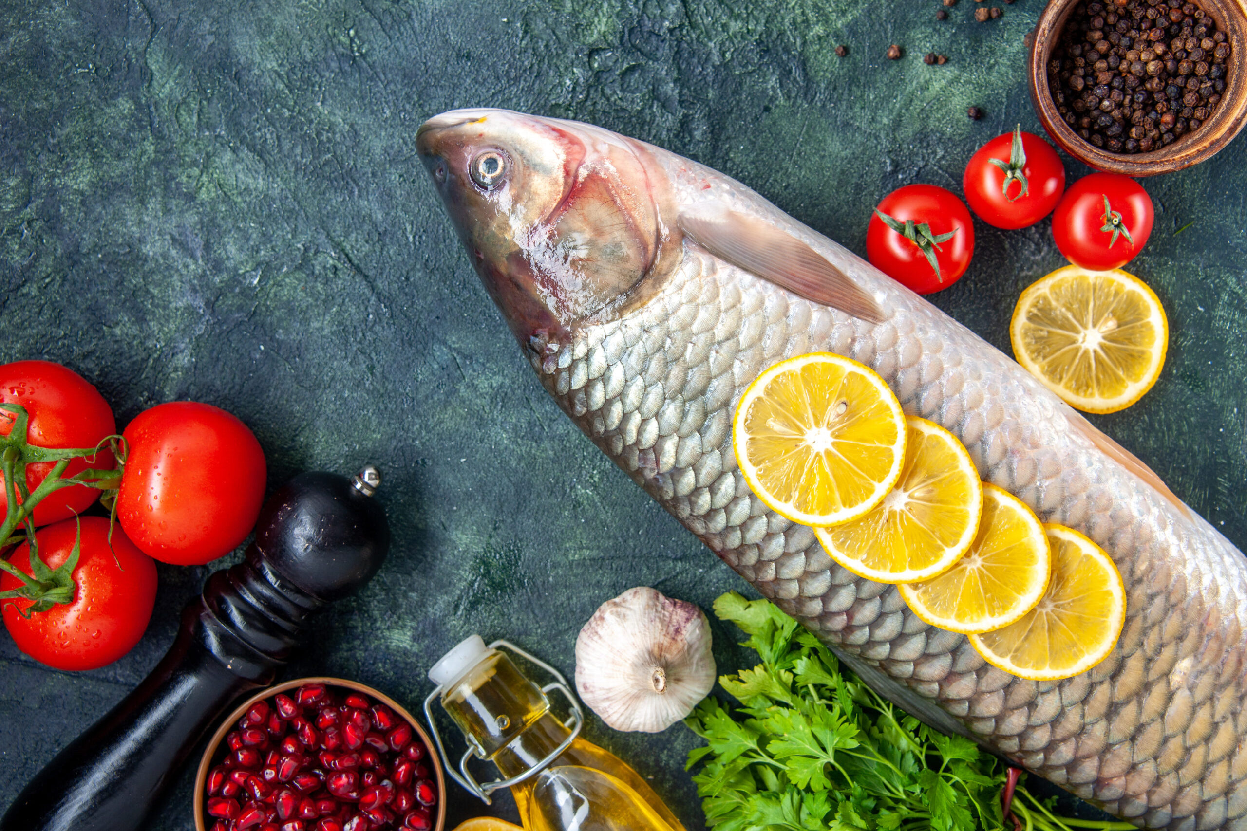 top-view-raw-fish-pepper-grinder-tomatoes-table