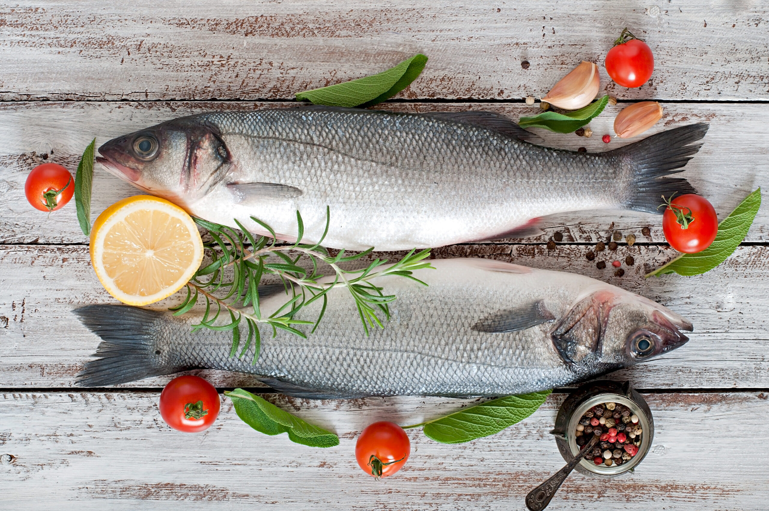 Two raw seabass with spices on an old wooden background.